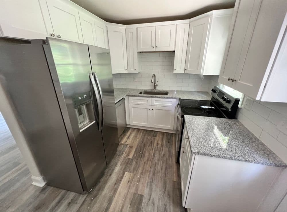 Modern kitchen with stainless steel appliances, white cabinets, and granite countertops.