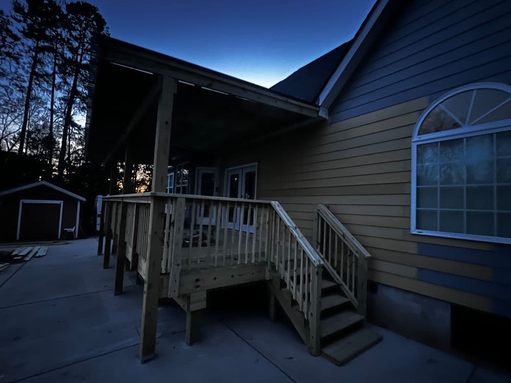 New wooden ramp and deck at a house during twilight, surrounded by trees.