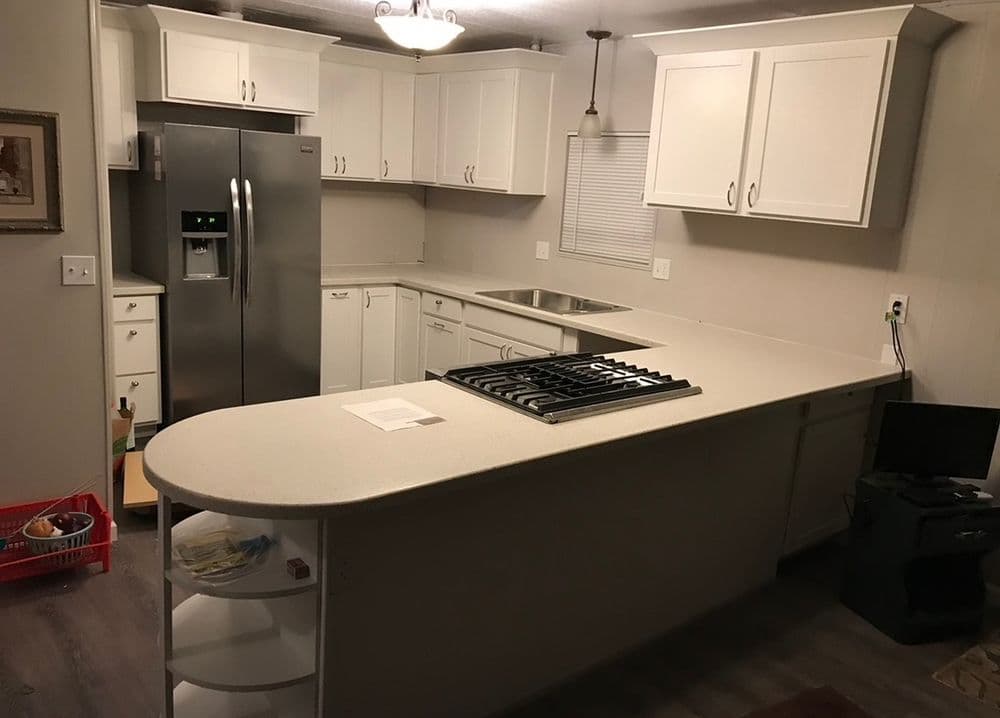 Modern kitchen with white cabinets, stainless steel fridge, and island with gas stove.