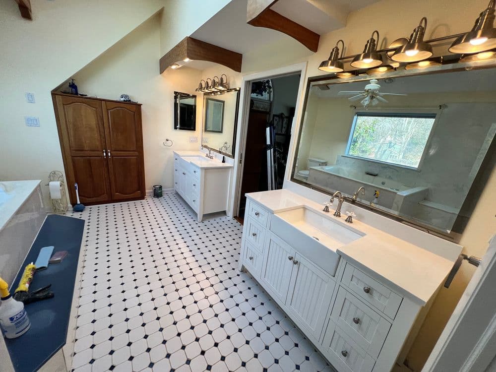Spacious modern bathroom with dual vanities, large mirrors, and tiled floor.