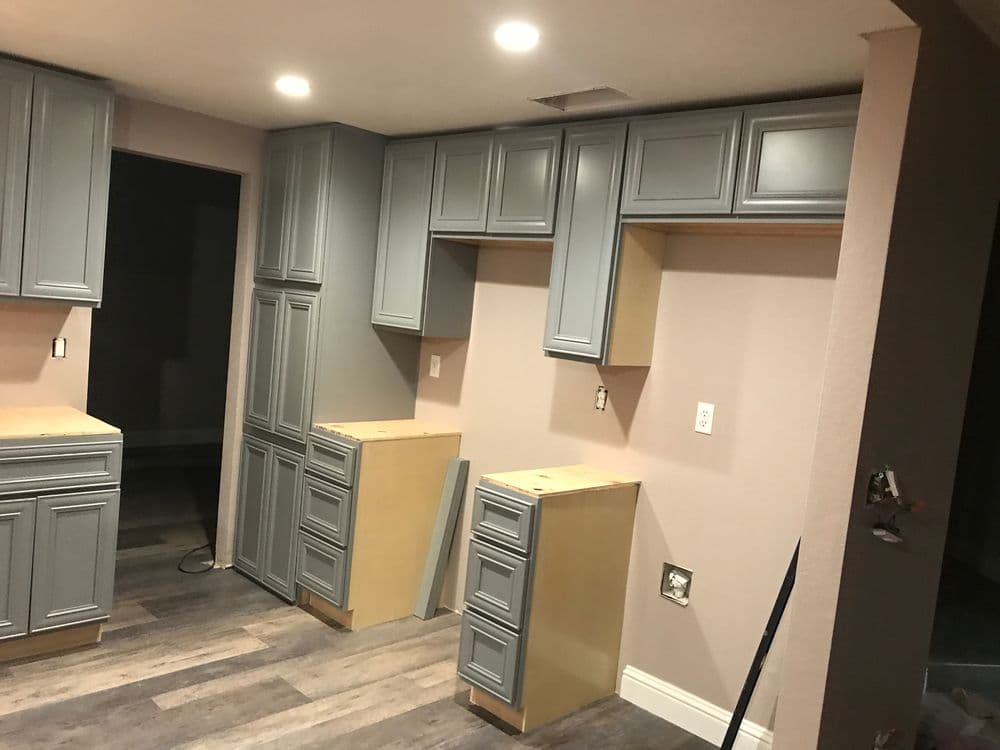 Modern kitchen with gray cabinets and unfinished wooden countertops, showcasing renovation progress.