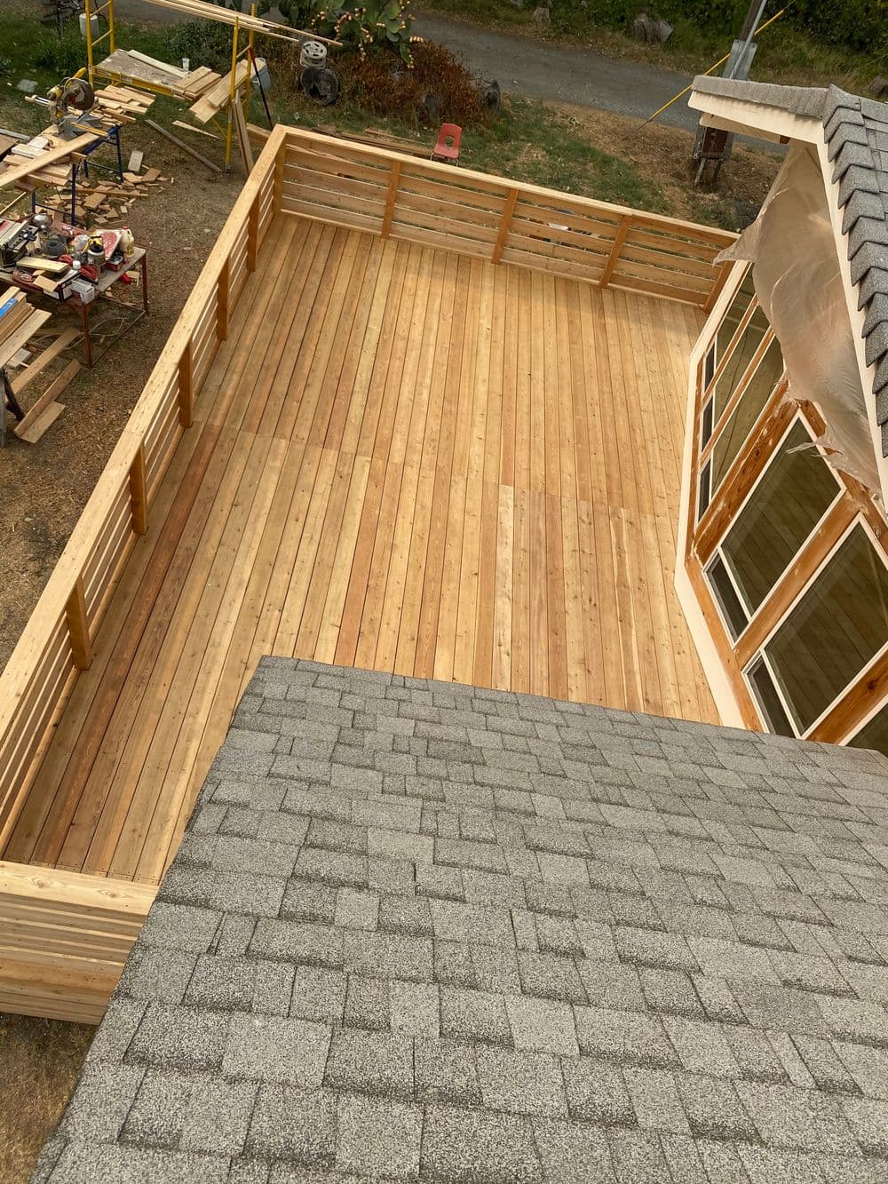 Aerial view of a newly constructed wooden deck adjacent to a house with shingles.