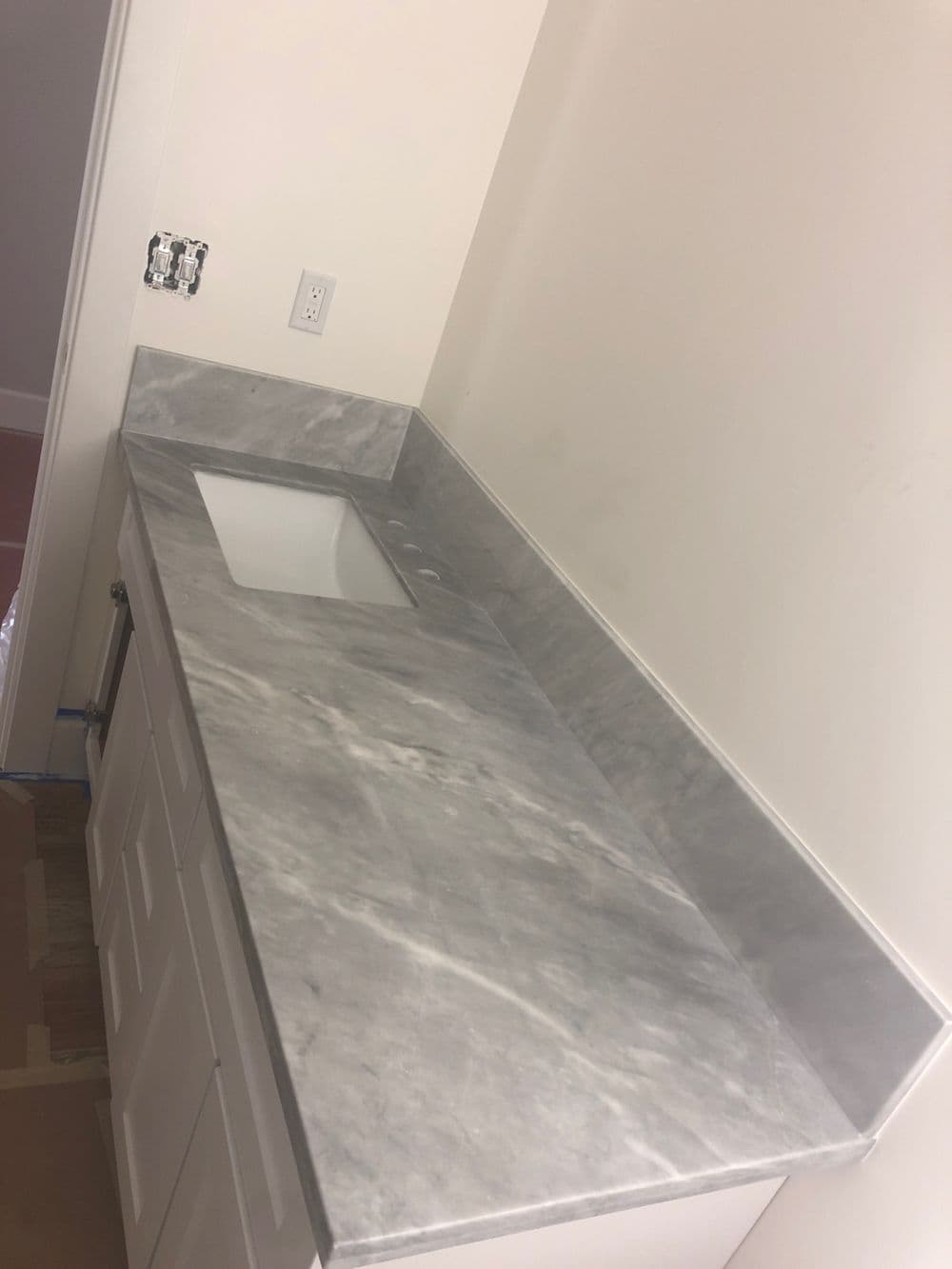 marble countertop with sink cutout in modern white bathroom cabinet design