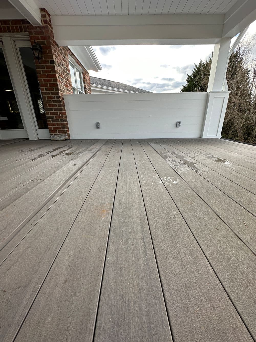 Modern wooden deck with gray planks and covered porch, showcasing clean lines and open space.