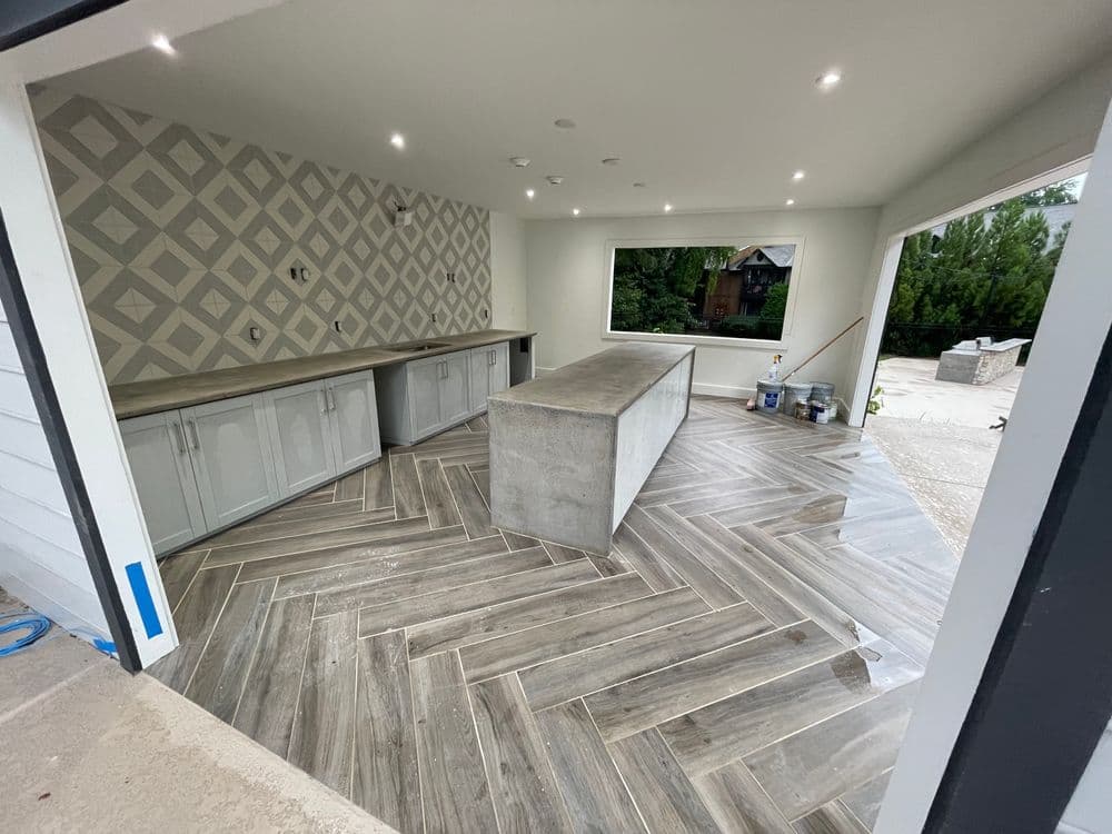 Modern kitchen design featuring a concrete island, herringbone flooring, and geometric backsplash.