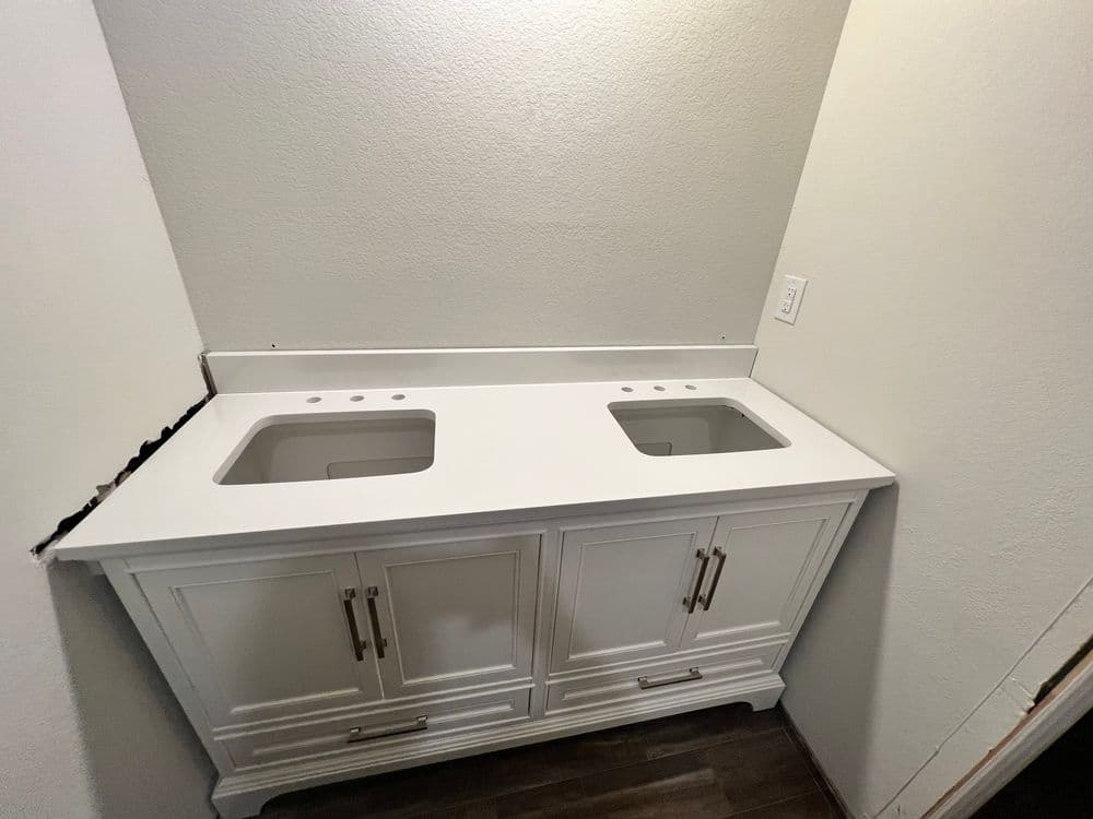 White bathroom vanity with double sink cutouts and stylish cabinet design against a light wall.