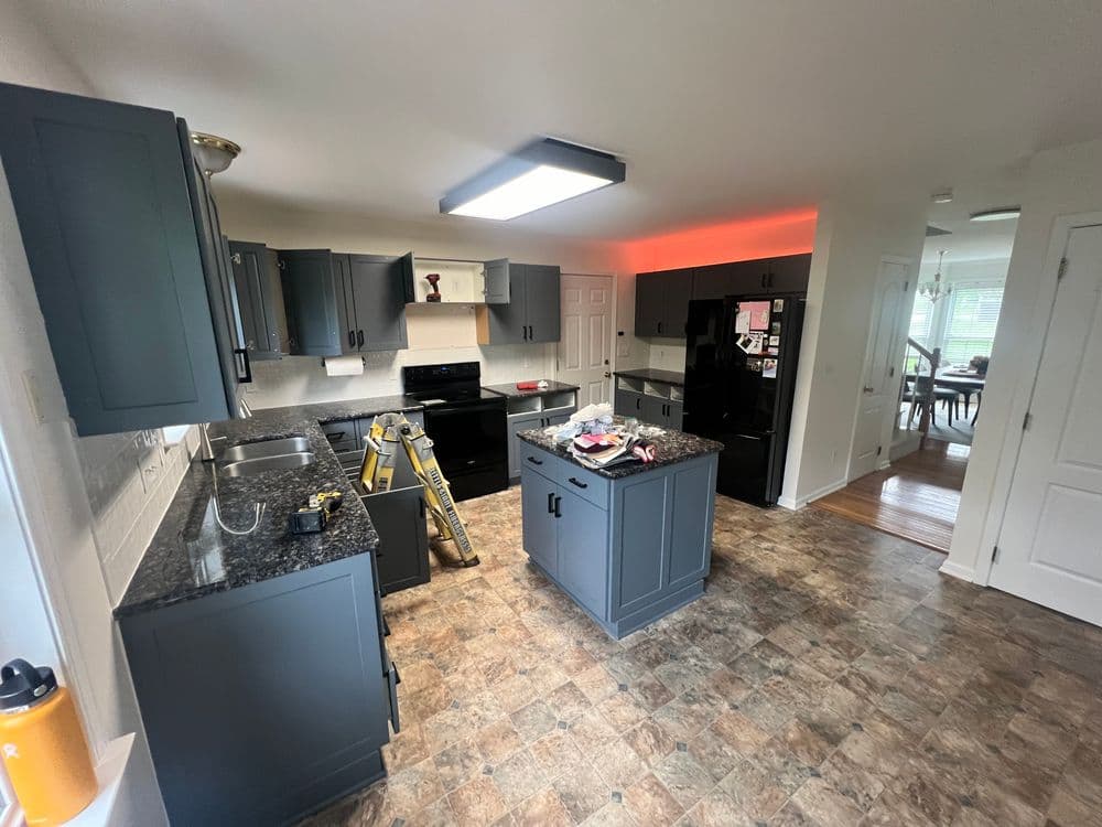 Modern kitchen renovation featuring dark cabinets, granite countertops, and stainless steel appliances.