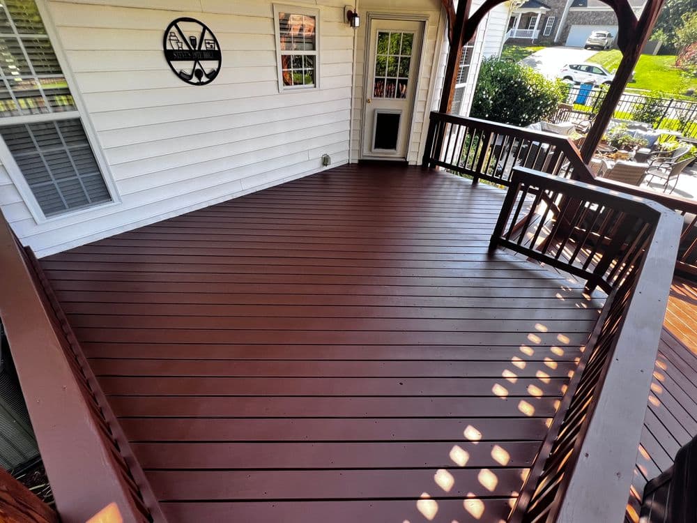 Well-maintained brown wooden deck under a covered porch with a wall decoration.