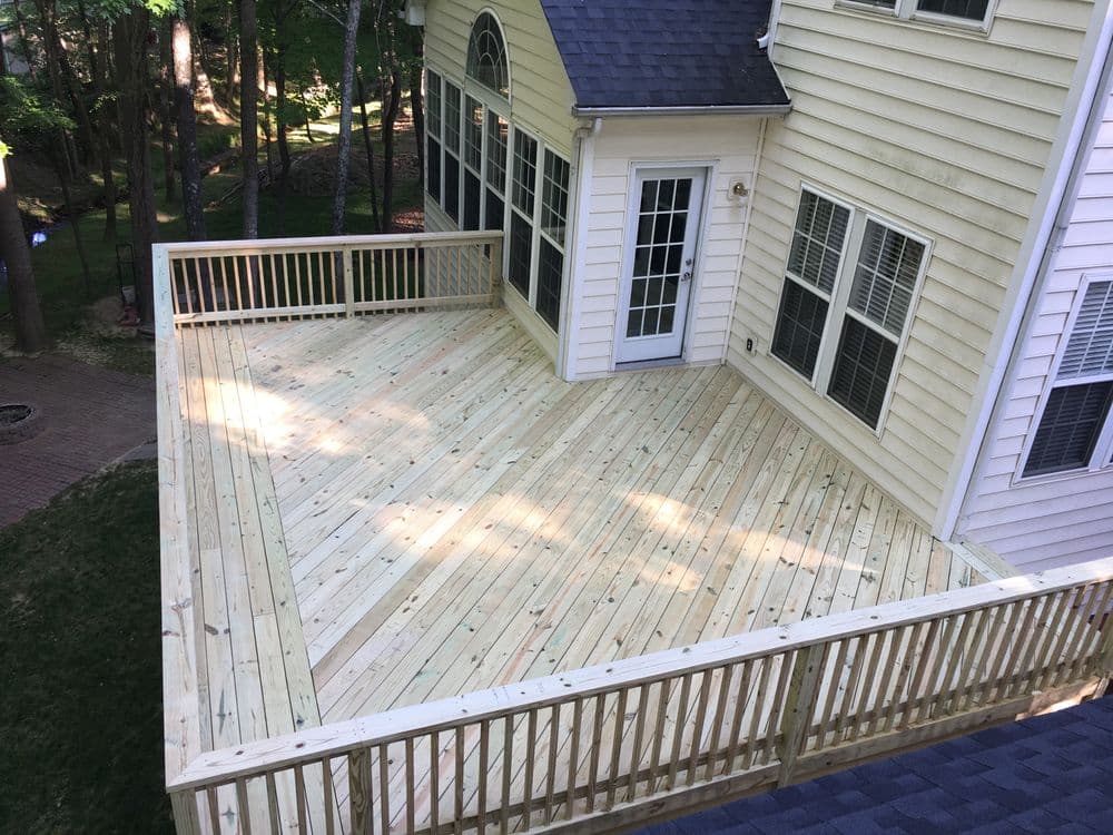 Newly constructed wooden deck overlooking a backyard, ideal for outdoor gatherings.