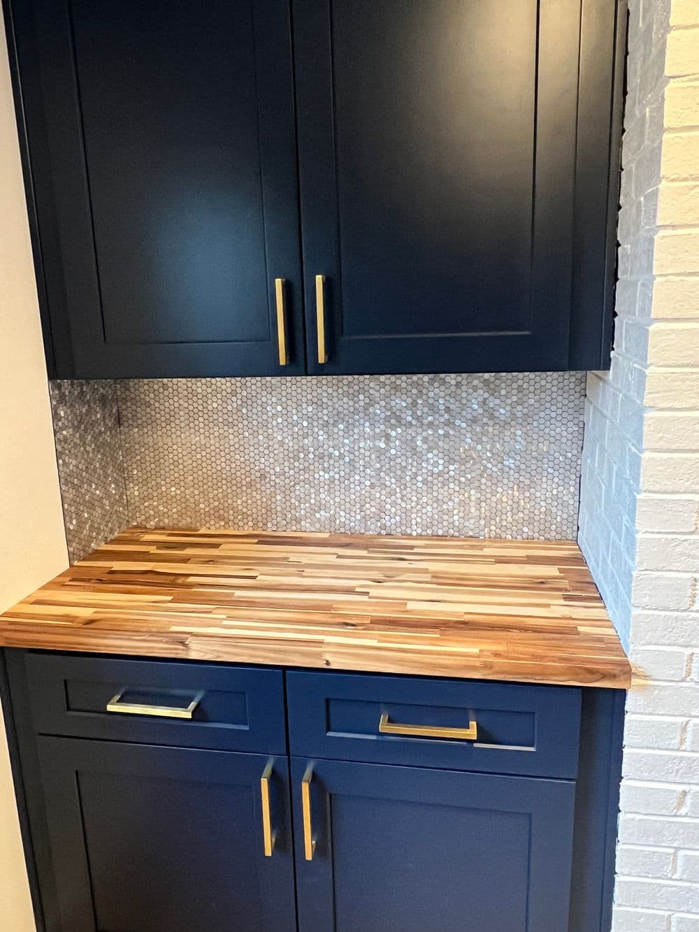Stylish kitchen corner with navy blue cabinets, wood countertop, and mosaic backsplash.