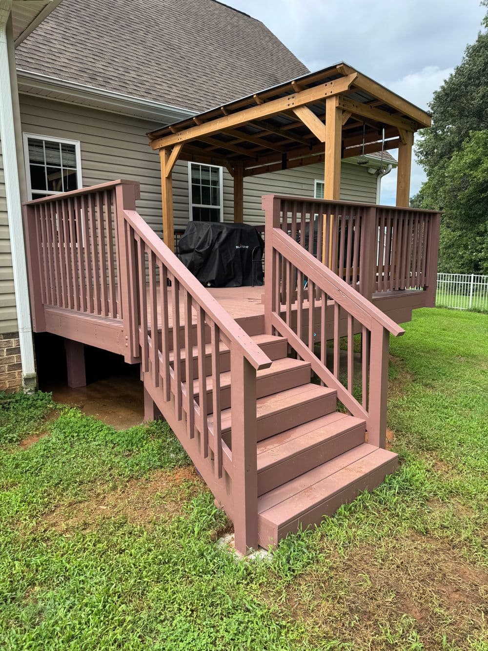 Accessible outdoor deck with a wooden gazebo and steps, surrounded by green grass.