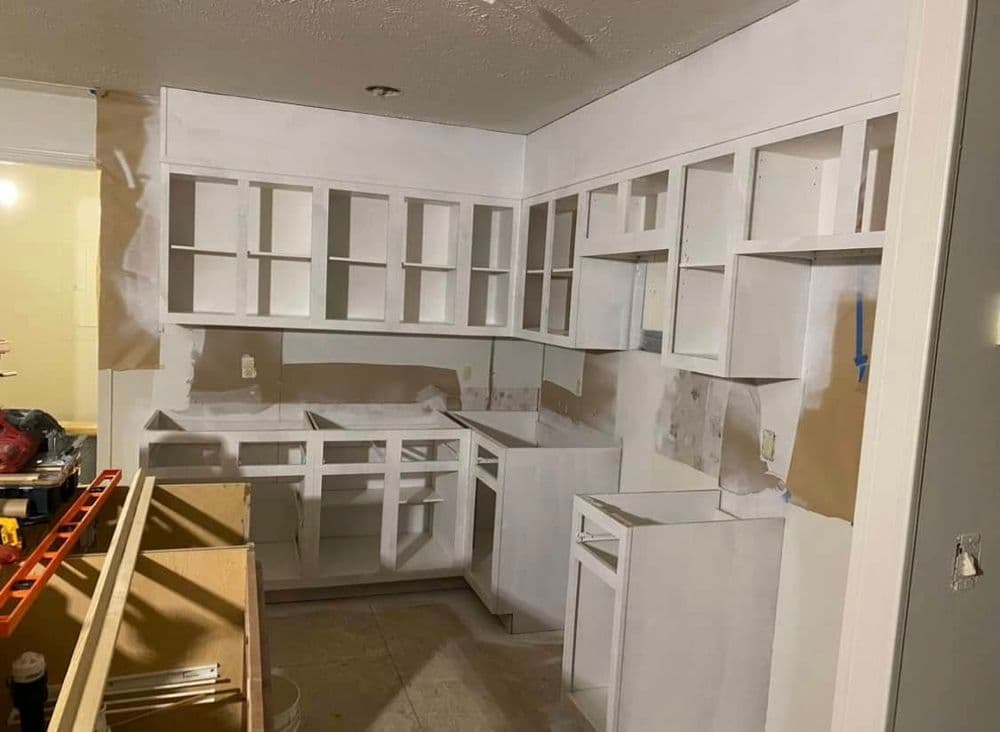 Renovated kitchen with unfinished white cabinets and empty countertops during installation.