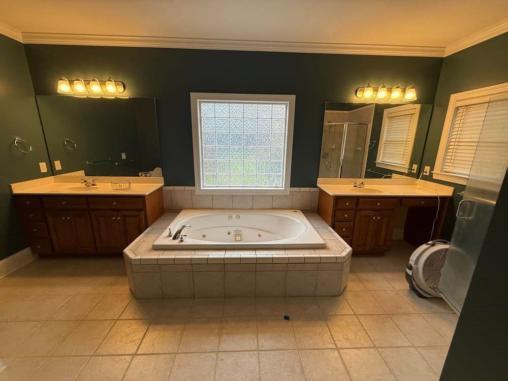 Spacious bathroom with a jacuzzi tub, dual vanities, and large windows for natural light.